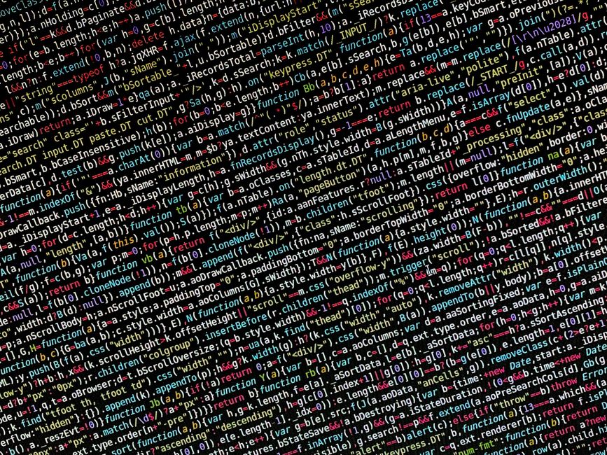 Close-up image of a computer screen displaying lines of HTML and programming code in various colors, including red, green, yellow, and white, set against a dark background. The code contains tags, fun